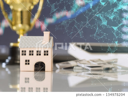 Miniature house with digital network overlay, cash, and financial chart, representing property investment, fintech, and real estate technology. 134978204