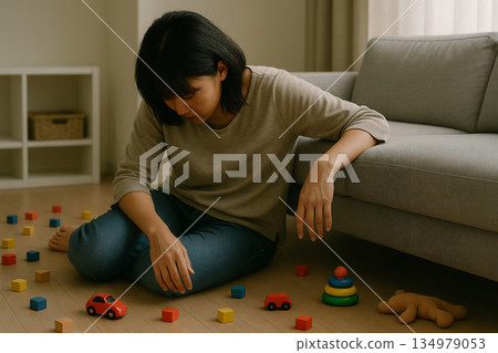 育兒場景:一位女士坐在地板上,擔心散落一地的玩具。 育兒場景:一位女士坐在地板上,擔心散落一地的玩具。 134979053