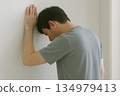 Indoor scene of a person feeling unwell with their hands on the wall 134979413