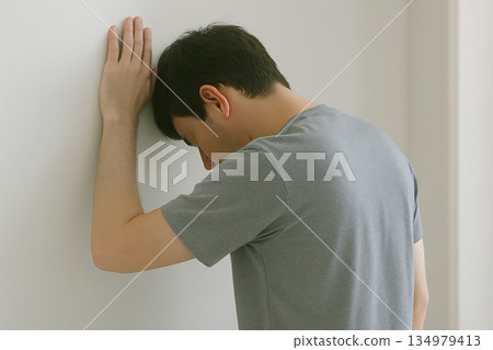 室內場景：一個人感到身體不適，雙手扶著牆。 134979413