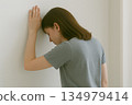 Back view of a person leaning against a wall and feeling unwell 134979414