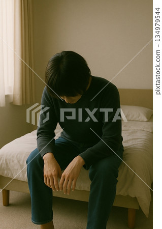 室內場景，一位女子坐在床上往下看。 134979544