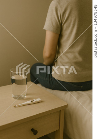 一位憂心忡忡的女子坐在床邊，背影朝後拍攝。 134979549