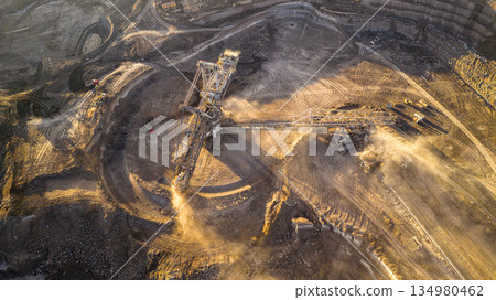 Ultra high resolution panoramic view of massive mining machines operating in an open pit coal mine, surrounded by dust and dramatic light. Powerful industrial scene showing large scale extraction, Ultra high resolution panoramic view of massive mining machines operating in an open pit coal mine, surrounded by dust and dramatic light. Powerful industrial scene showing large scale extraction, 134980462