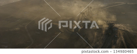Ultra high resolution panoramic view of massive mining machines operating in an open pit coal mine, surrounded by dust and dramatic light. Powerful industrial scene showing large scale extraction, Ultra high resolution panoramic view of massive mining machines operating in an open pit coal mine, surrounded by dust and dramatic light. Powerful industrial scene showing large scale extraction, 134980465