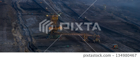 Ultra high resolution panoramic view of massive mining machines operating in an open pit coal mine, surrounded by dust and dramatic light. Powerful industrial scene showing large scale extraction, 134980467