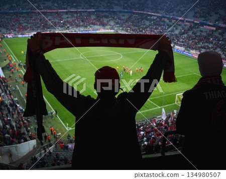 Man is holding a red scarf and is watching a soccer game 134980507
