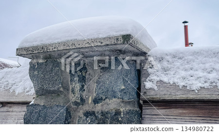 Massive stone fence post covered with a thick layer of fresh white snow in a winter countryside Massive stone fence post covered with a thick layer of fresh white snow in a winter countryside 134980722