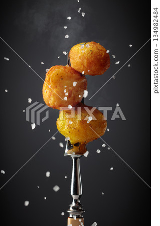 Roasted potatoes on a fork sprinkled with sea salt. 134982484