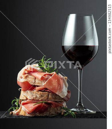 Ciabatta with prosciutto, rosemary and glass of red wine. Ciabatta with prosciutto, rosemary and glass of red wine. 134982515