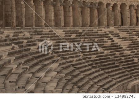 Part of the amphitheater with a stone staircase and a wall in the background. The wall has arches Part of the amphitheater with a stone staircase and a wall in the background. The wall has arches 134982743