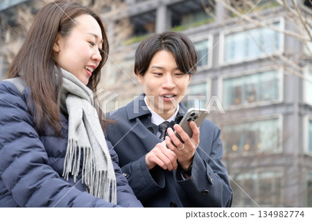 Men and women using smartphones in an office district Men and women using smartphones in an office district 134982774