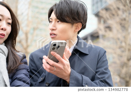 Men and women using smartphones in an office district Men and women using smartphones in an office district 134982778