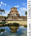 Wat Mahathat ruins and stone statues in Sukhothai Historical Park reflected in the water 134982973