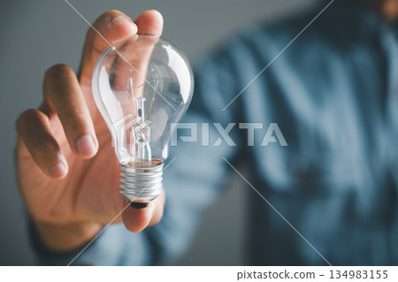 Close-up of a hand holding a lightbulb, symbolizing a new idea or solution. The background is blurred, leaving the lightbulb as the focal point. . Close-up of a hand holding a lightbulb, symbolizing a new idea or solution. The background is blurred, leaving the lightbulb as the focal point. . 134983155