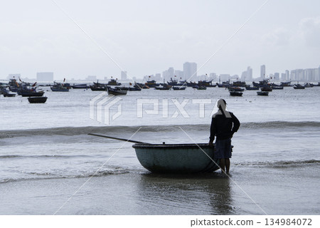 Vietnamese fisherman with traditional basket boat on the sea shore Vietnamese fisherman with traditional basket boat on the sea shore 134984072