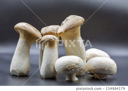 Fresh eringi oyster and champignon mushrooms on black surface closeup. 134984179