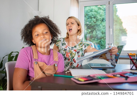 Stressed mother struggling with unmotivated child doing homework 134984701