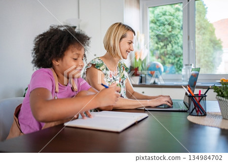Mother and daughter learning studying together at home desk 134984702