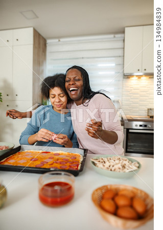 Mother and daughter bonding making pizza together 134984839