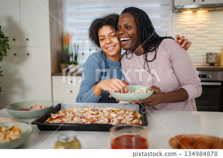 Mother and daughter bonding preparing pizza in kitchen Mother and daughter bonding preparing pizza in kitchen 134984878