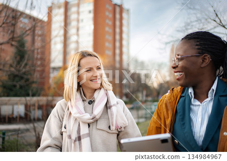 Diverse women friends smiling walking talking outdoors Diverse women friends smiling walking talking outdoors 134984967