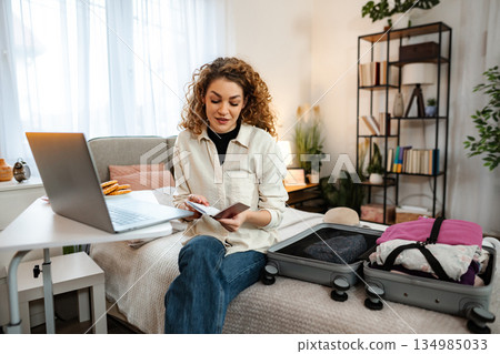 Young woman packing suitcase for travel planning vacation 134985033