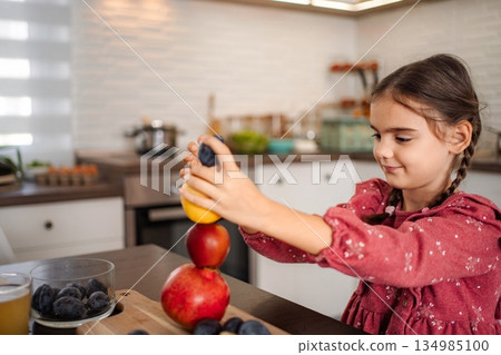 Young girl playing with fruits at kitchen counter Young girl playing with fruits at kitchen counter 134985100