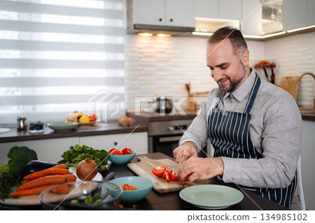 Mid adult man enjoying cooking healthy meal in modern kitchen 134985102