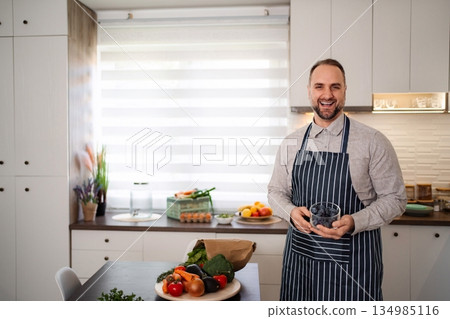 Man in kitchen preparing healthy meal with fresh blueberries 134985116