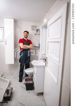 Plumber smiling with arms crossed after installing bathroom fixtures 134985593