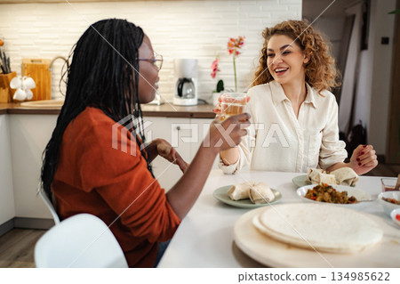 Diverse friends enjoying meal and talking in kitchen Diverse friends enjoying meal and talking in kitchen 134985622