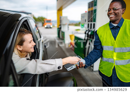 Woman paying for gas with credit card at service gas station 134985629