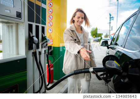Woman smiling while refueling car at a gas station 134985643
