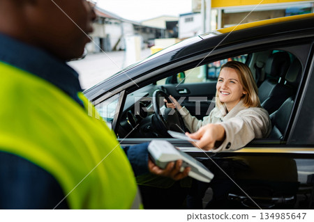 Woman paying for gas fueling car with credit card at service station 134985647