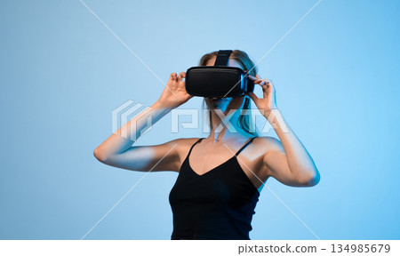 Female user in VR headset exploring virtual space with hand gestures, immersive digital experience and modern technology concept 134985679