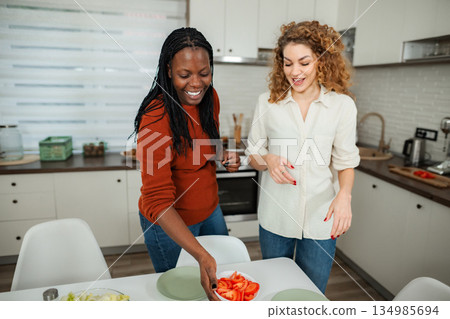 Diverse women friends preparing fresh salad for healthy meal 134985694