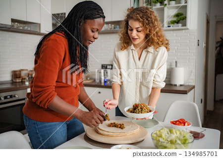 Friends preparing healthy tacos in domestic kitchen Friends preparing healthy tacos in domestic kitchen 134985701