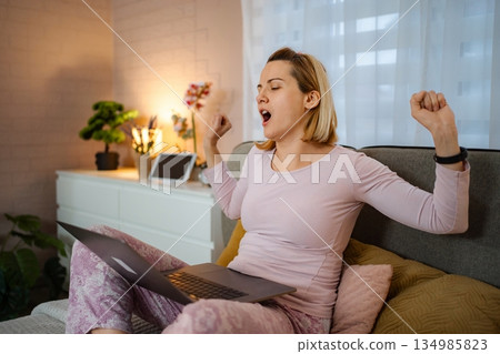 Woman yawning while working from home in pajamas 134985823