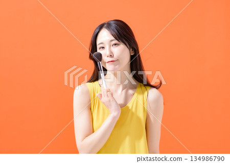 Woman holding a makeup brush Woman holding a makeup brush 134986790