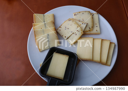 sliced cheese pieces for a traditional raclette lunch sliced cheese pieces for a traditional raclette lunch 134987990