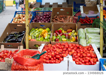 Brightly colored vegetables in crates at an open-air farmers' market. Fresh eggplants, onions, tomatoes, and peppers at a produce market Brightly colored vegetables in crates at an open-air farmers' market. Fresh eggplants, onions, tomatoes, and peppers at a produce market 134988026