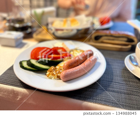 Breakfast plate with sausages eggs and fresh vegetables on table. Morning routine, balanced nutrition, casual dining and everyday comfort food concept 134988045