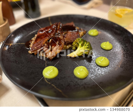 Gourmet meat dish with broccoli and green sauce. Fine dining, modern cuisine, restaurant presentation, and culinary aesthetics Gourmet meat dish with broccoli and green sauce. Fine dining, modern cuisine, restaurant presentation, and culinary aesthetics 134988070