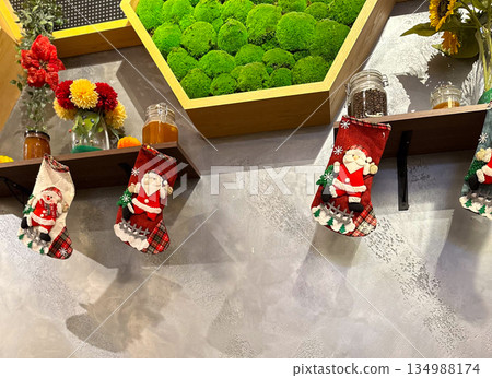 Christmas stockings hanging on wall shelf with festive decor. Seasonal styling, holiday atmosphere, interior design detail, winter tradition, and cozy decorative accents in public space. Christmas stockings hanging on wall shelf with festive decor. Seasonal styling, holiday atmosphere, interior design detail, winter tradition, and cozy decorative accents in public space. 134988174