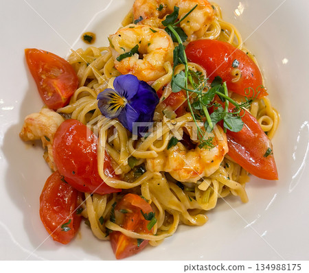 Pasta with shrimp and tomatoes served on white plate close-up. Culinary presentation, gourmet dining, balanced nutrition, seafood cuisine, and sensory enjoyment through refined food preparation. Pasta with shrimp and tomatoes served on white plate close-up. Culinary presentation, gourmet dining, balanced nutrition, seafood cuisine, and sensory enjoyment through refined food preparation. 134988175