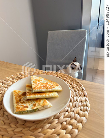 Pan fried flatbread slices served on a plate on a wooden dining table at home. Cozy breakfast moment, everyday domestic food routine and quiet morning lifestyle 134988227