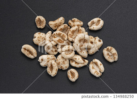 Puffed wheat pile isolated on black background, cereal breakfast grains, top view, full depth of field Puffed wheat pile isolated on black background, cereal breakfast grains, top view, full depth of field 134988250