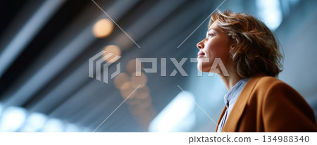 Side profile of confident young woman looking upwards with thoughtful expression in modern indoor setting with blurred lights Side profile of confident young woman looking upwards with thoughtful expression in modern indoor setting with blurred lights 134988340