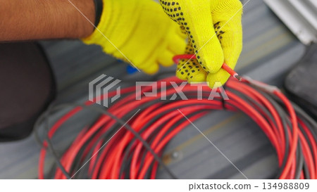 Electrician technician worker with wire stripper plier prepares the electric cable in electrical system. Electrician installing wires. A professional electrician removes electrical insulation. Electrician technician worker with wire stripper plier prepares the electric cable in electrical system. Electrician installing wires. A professional electrician removes electrical insulation. 134988809